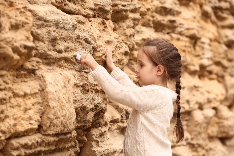 ילדה מטמינה פתק בכותל. צילום: שאטרסטוק